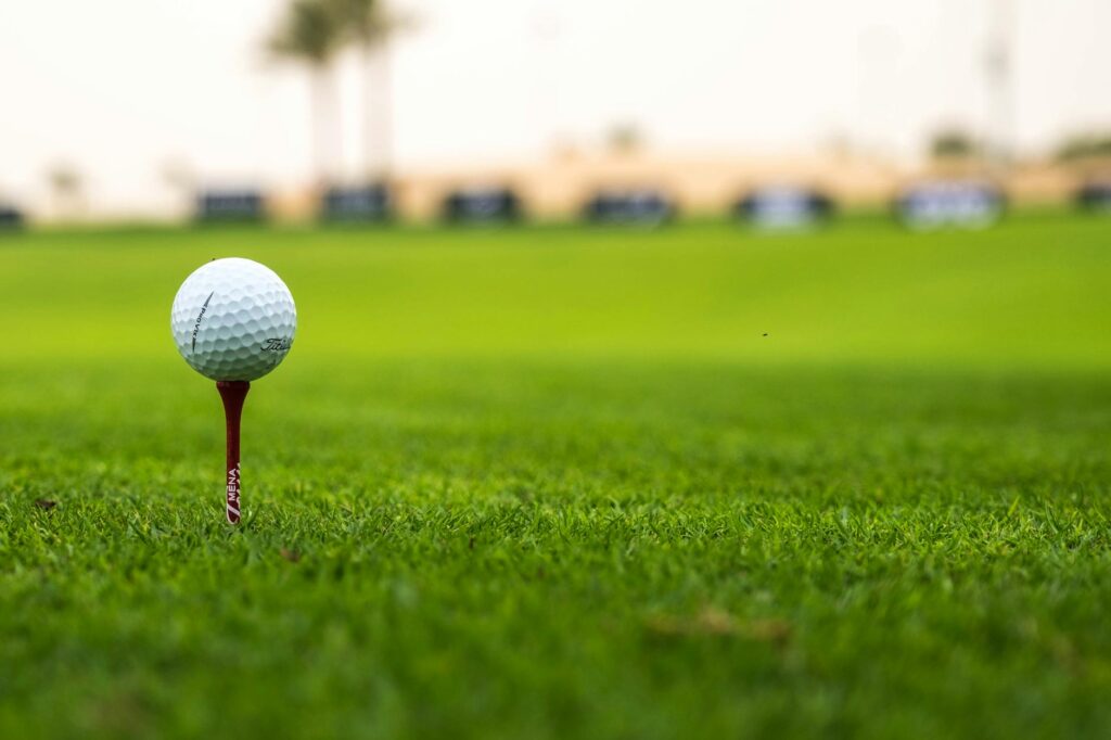 A close-up of a golf ball on a tee with a Dungeness course in the background — Dungeness golf courses