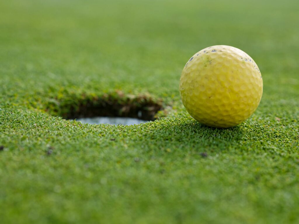 A close-up of a golf ball on a wet green, illustrating rain conditions. — ideal weather for golf swing
