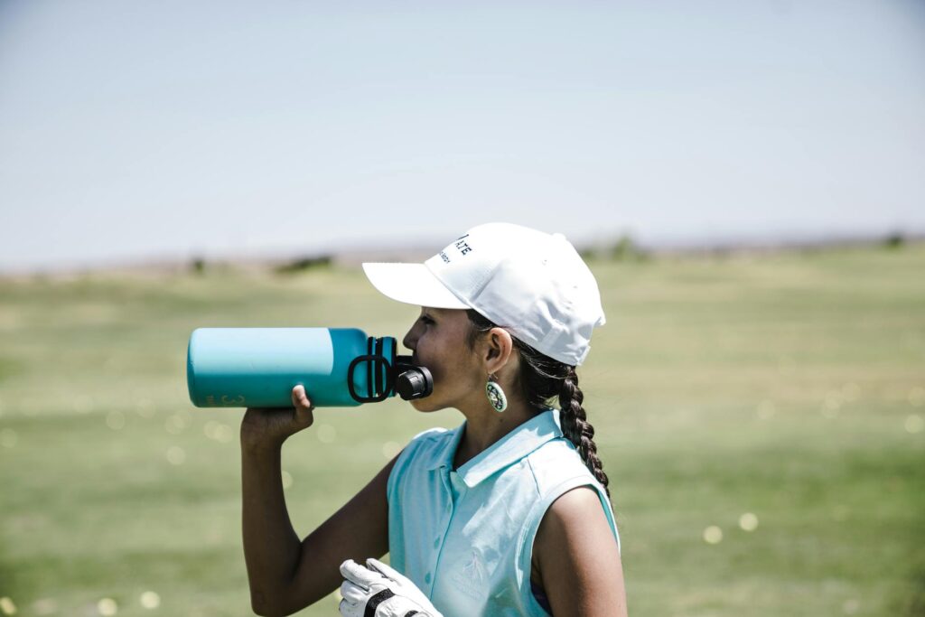 A close-up of a golfer drinking water on the course to stay hydrated — golfing safety high altitude