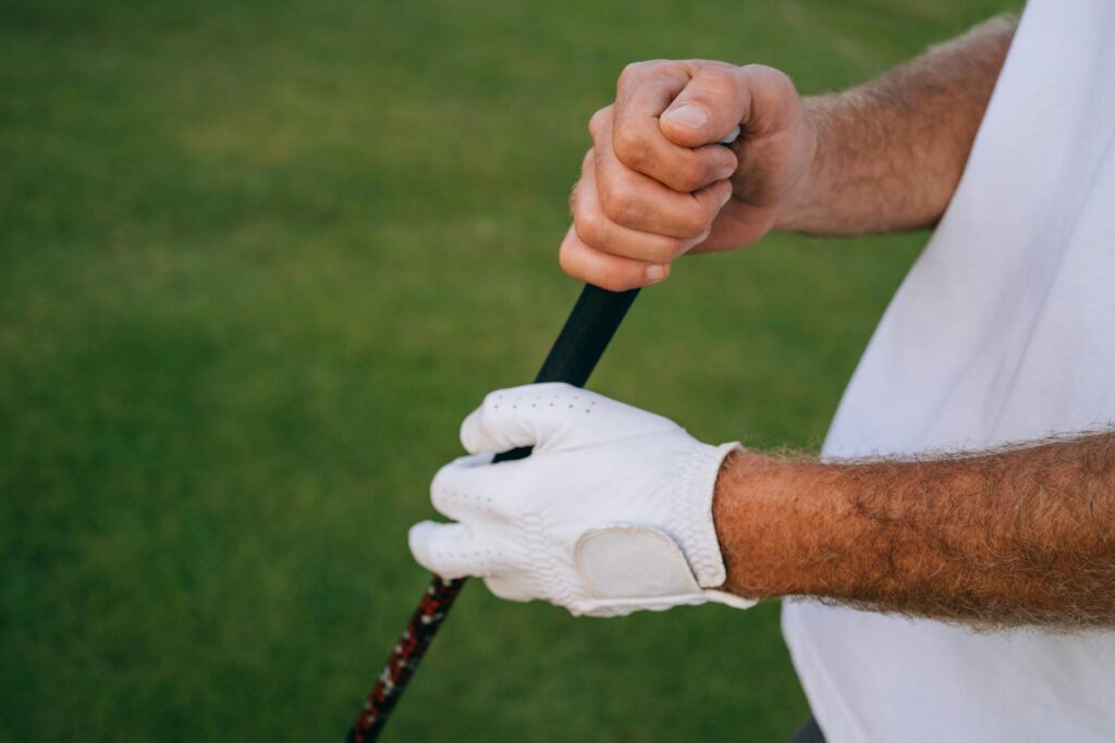 A close-up of a golfer's hands gripping a club with cold weather gloves. — golf swing cold weather