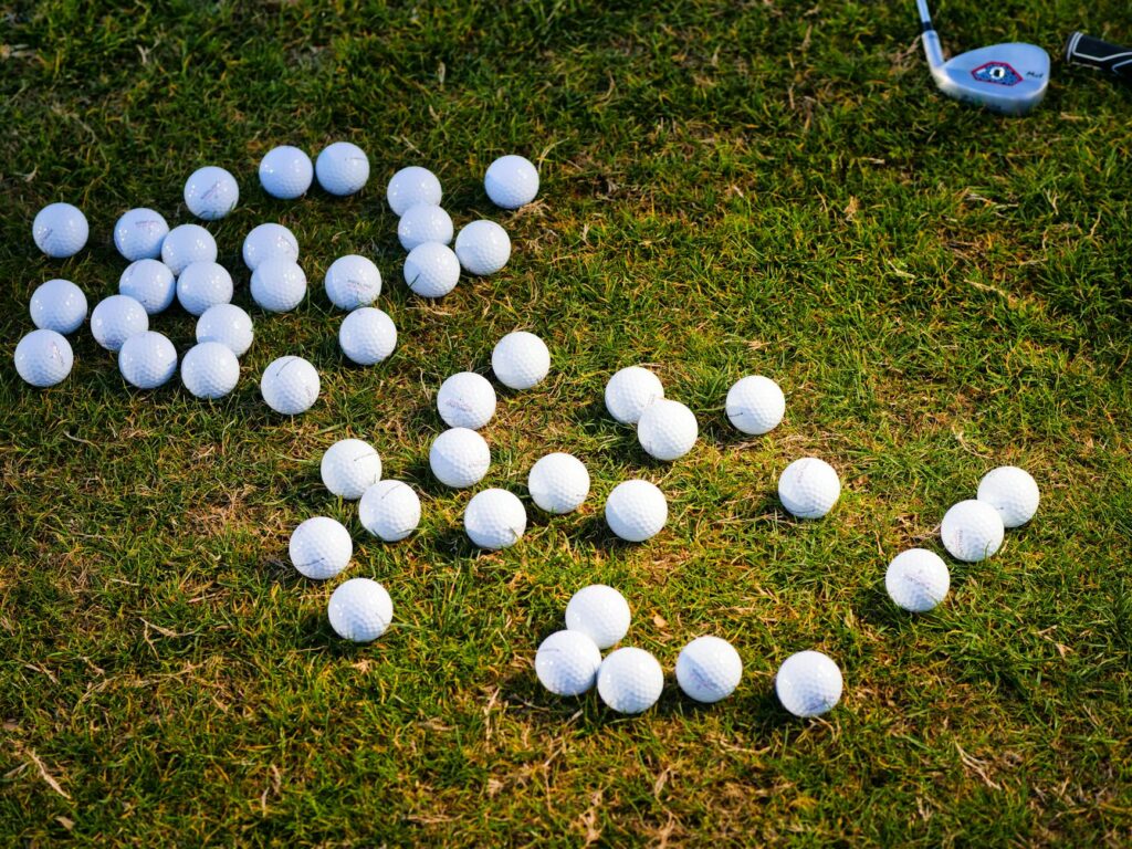 A close-up of various golf balls and tees laid out on a golf course. This image supports your golf packing list Dungeness.