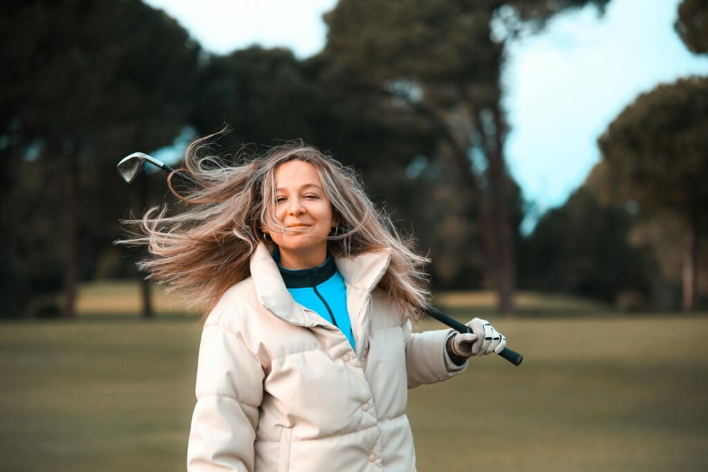 A golfer practicing their swing with wind blowing, showcasing wind impact. — ideal weather for golf swing