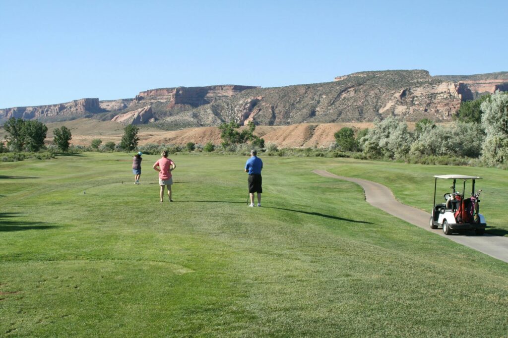 A group of friends enjoying a round of golf in a scenic mountainous setting. — high altitude golf tournaments