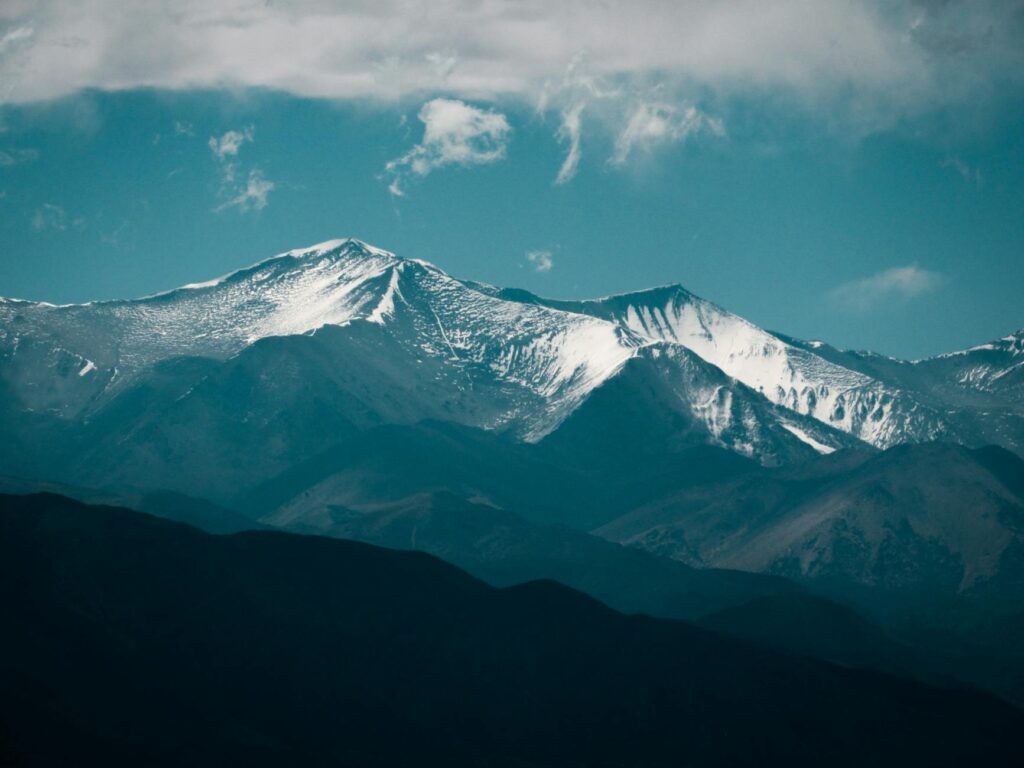 A high altitude golf course with snow-capped mountains in the background, showcasing the beauty and challenges of climate change high altitude golf.
