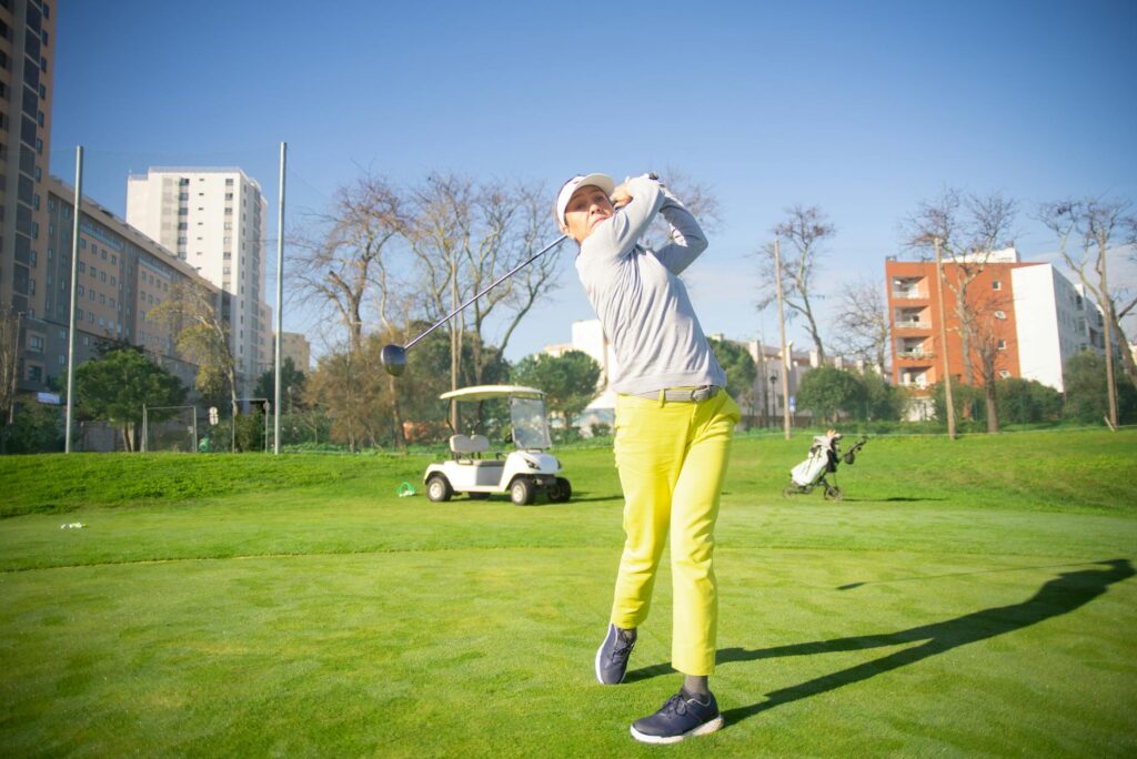 A woman swinging a golf driver on the course — best golf driver for women