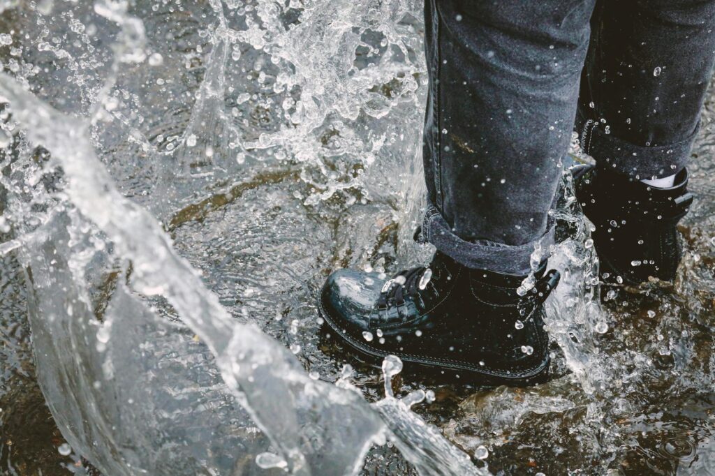 Close-up of waterproof golf shoes splashing through puddles. — golf gear wet weather