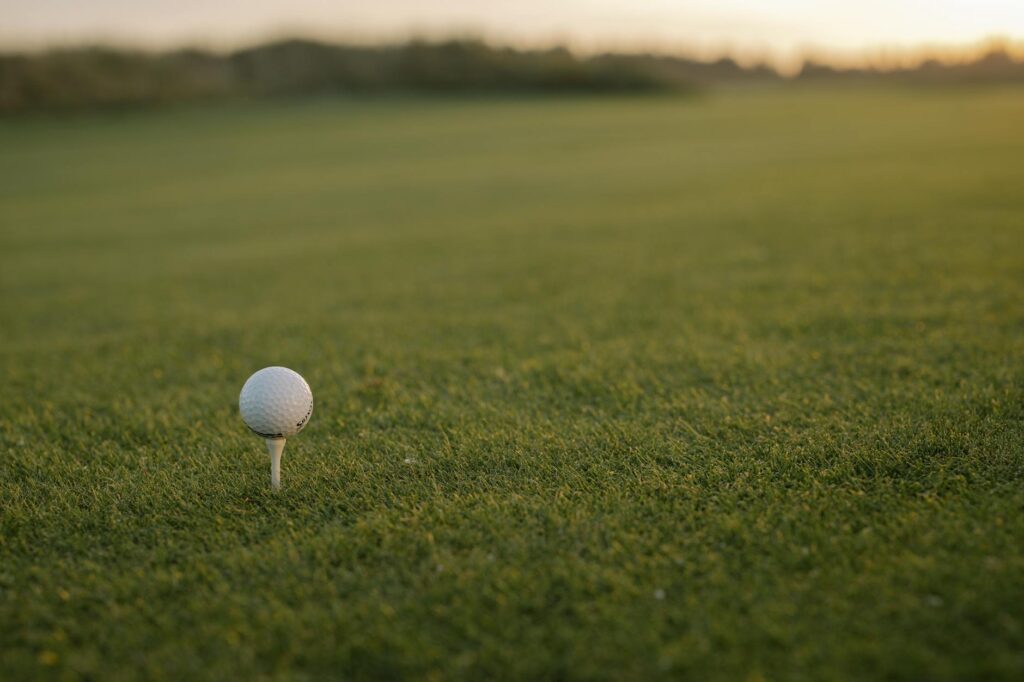 A close-up of a golf ball resting on a tee at a Dungeness course during sunset. — Dungeness golf courses