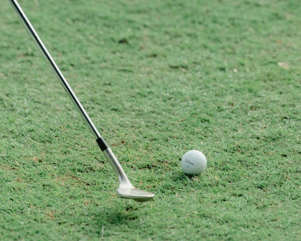 A close-up of a golf club hitting a ball, showcasing the follow-through. — lower golf score tips