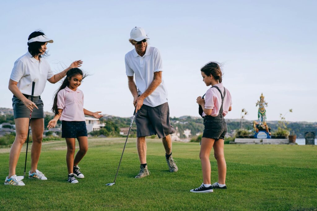 A family enjoying a day of golf at a Dungeness course, with kids swinging clubs and parents encouraging them. — family g…