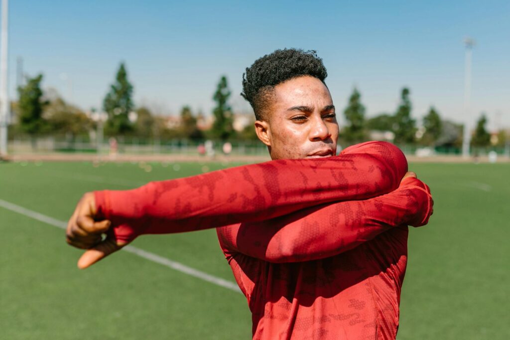 A golfer performing dynamic stretches with arm circles in a park setting. — golf warm-up exercises