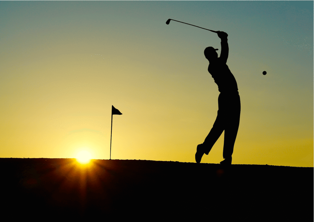 A golfer teeing off at Troon North Golf Club with the sun setting in the background. — best golf courses in Arizona