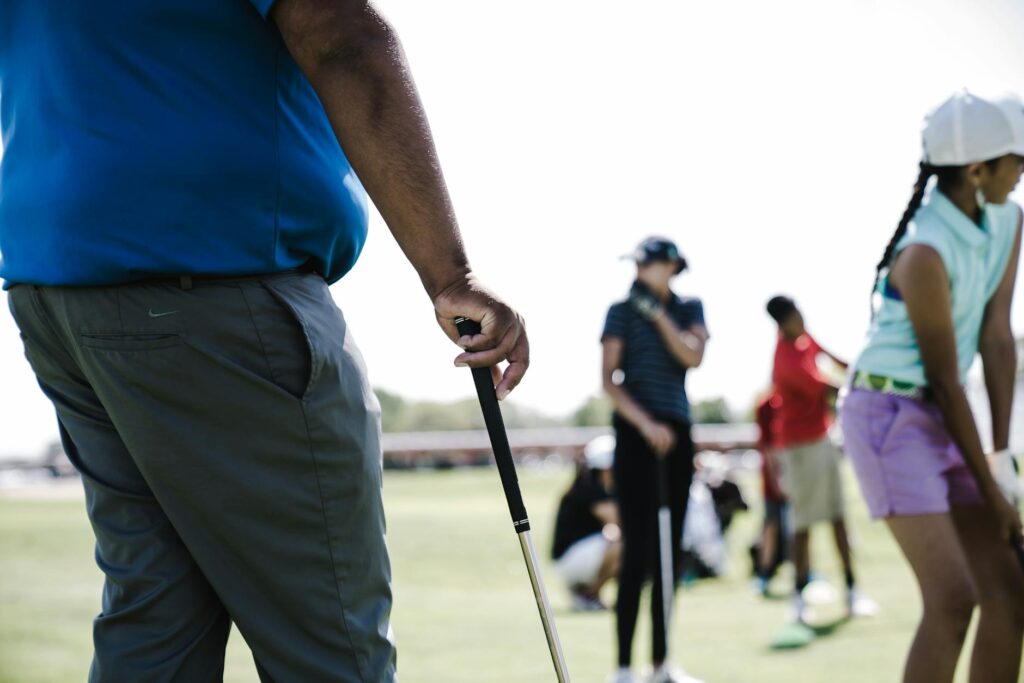 A group of golfers participating in a training session at a Dungeness facility, focused on improving their golf swing. —…