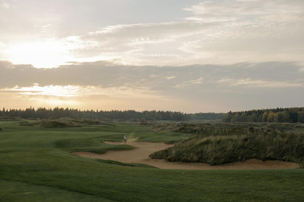 A scenic view of a Dungeness golf course at sunrise with beginners practicing. — Dungeness golf courses for beginners