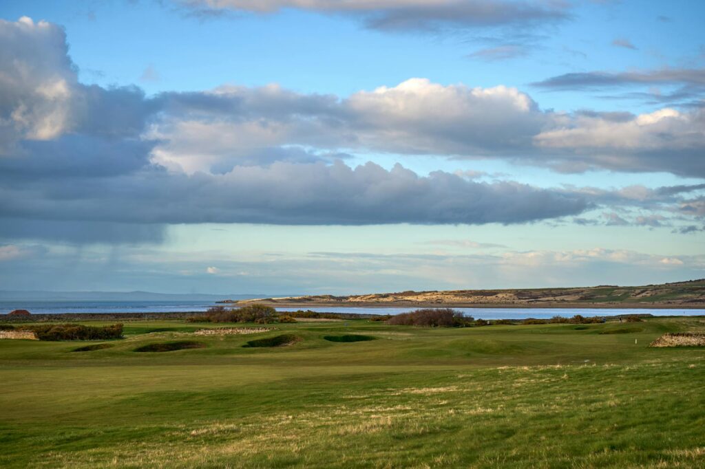 A scenic view of a golf course in Scotland, with rolling hills and ancient castles in the distance. — scenic golf courses