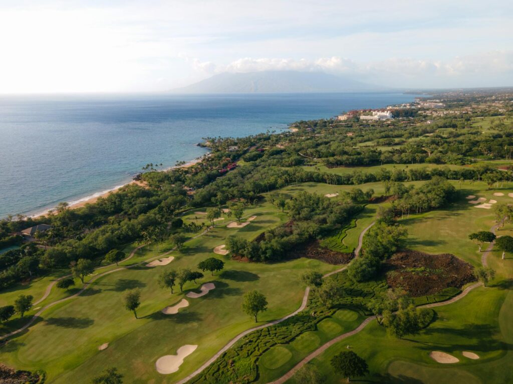 Aerial view of a lush Dungeness golf course with mountains in the background. — Dungeness golf courses