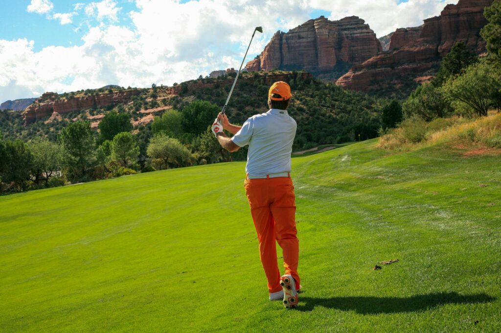 Close-up of a golfer taking a swing with the scenic backdrop of mountains — Dungeness golf course views