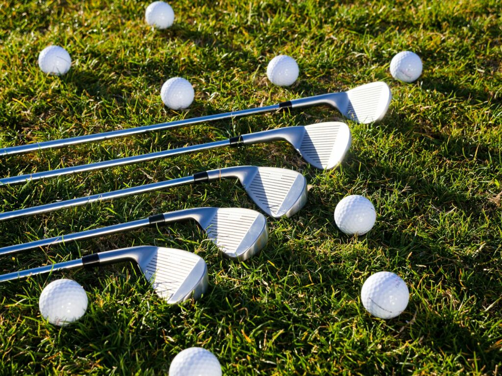 Golf clubs and balls laid out on a green grass surface. — golfing tips Dungeness