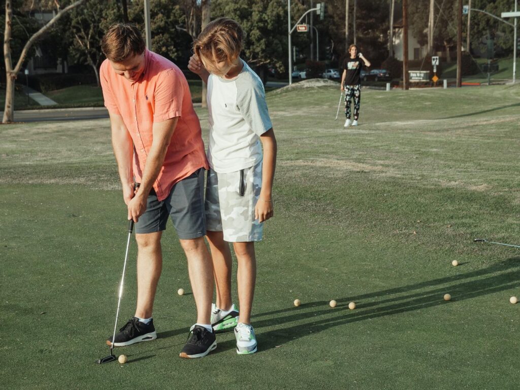 Parents and children practicing putting on a well-maintained green. — family golf Dungeness