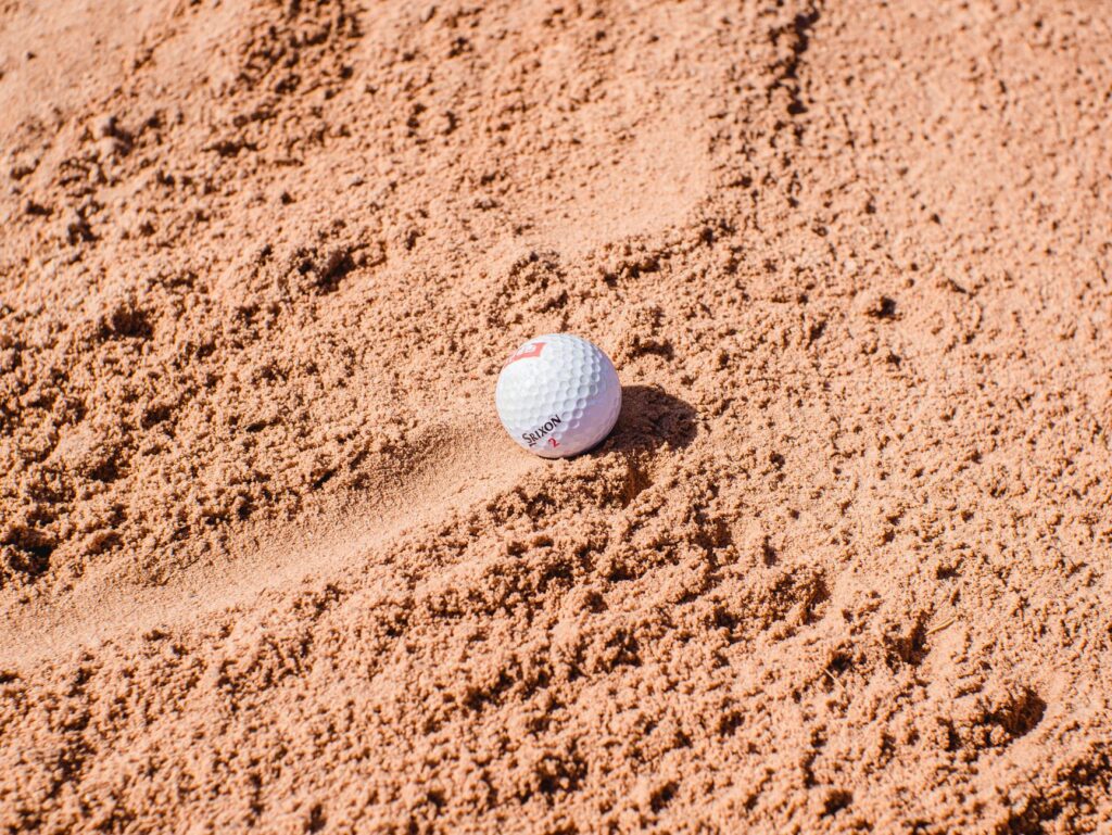 A close-up of a golf ball in a bunker with rule guidelines displayed. — golf rules guide