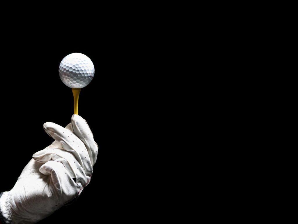 A close-up of a golf ball on a tee with a dramatic sky in the background. — best times to play golf in Dungeness