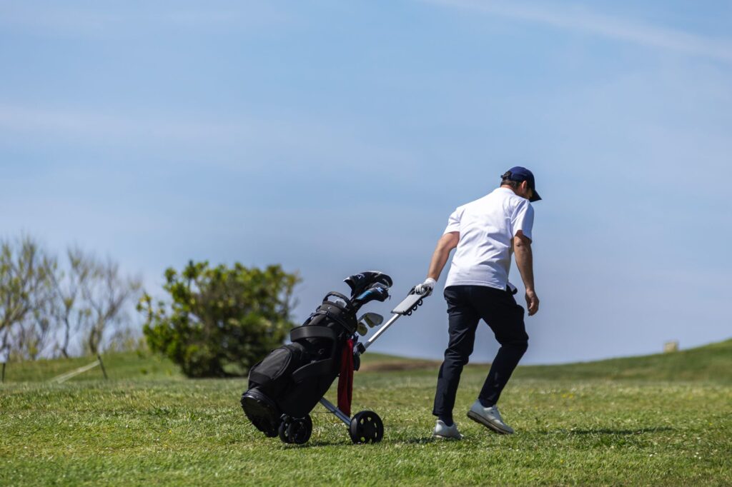 A golfer walking the course with clubs, showcasing the benefits of walking for golf fitness. — walking vs riding golf