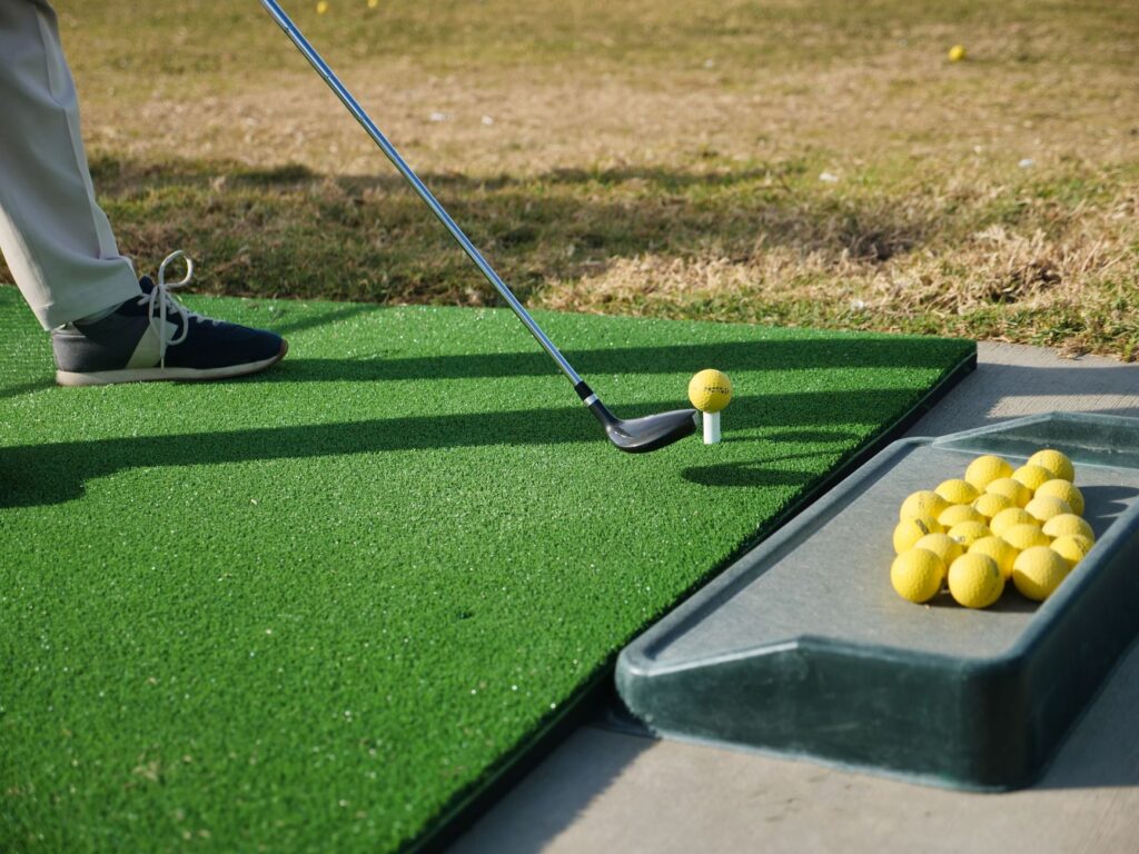 An impact bag set up on the turf with a golfer practicing their swing. — golf practice drills