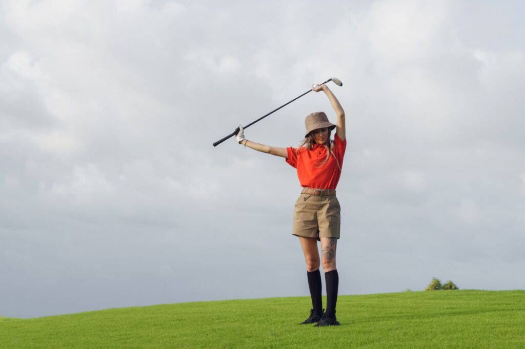 A golfer adjusting their cap while standing on the Dungeness golf course with cloudy skies. — golf in Dungeness weather