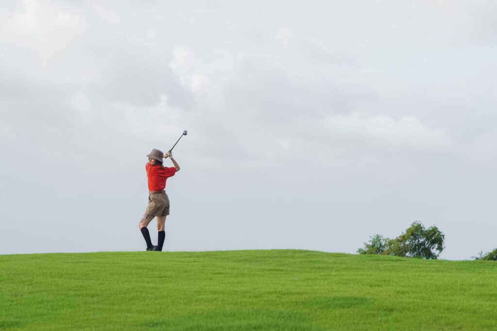 A golfer swinging in Dungeness with overcast skies in the background — golf equipment Dungeness