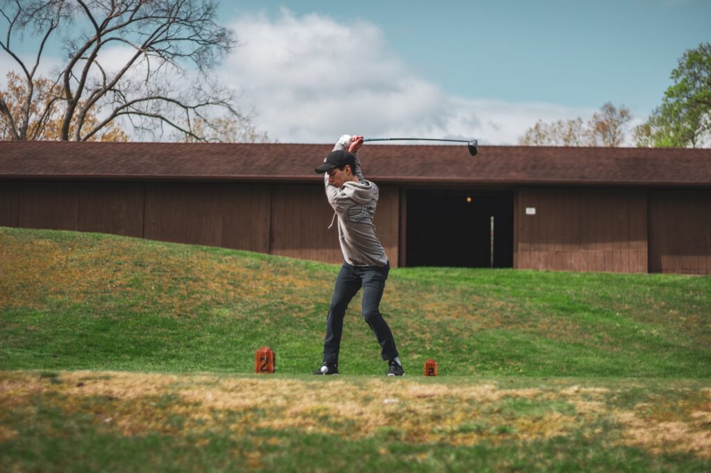 An action shot of a golfer making a powerful drive on the course, highlighting long drive control