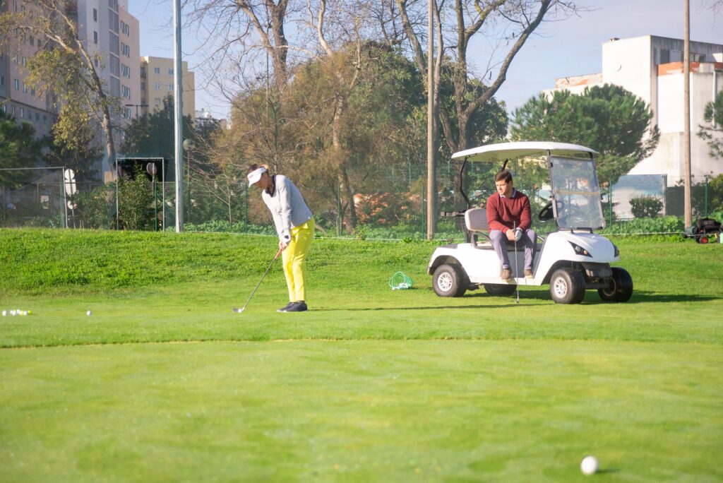 A beginner golfer taking a swing while a friend watches and gives tips. — beginner golf Dungeness