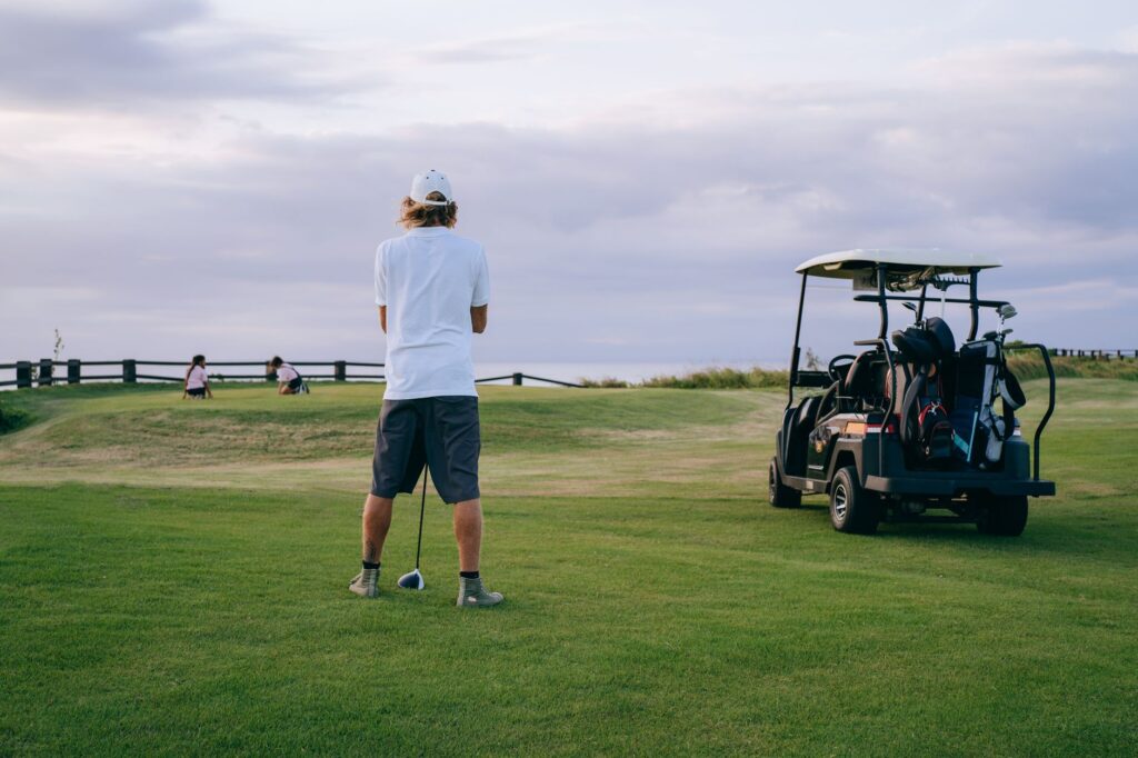 A beginner golfer teeing off with a beautiful Dungeness landscape in the background. — Dungeness golf courses for beginners