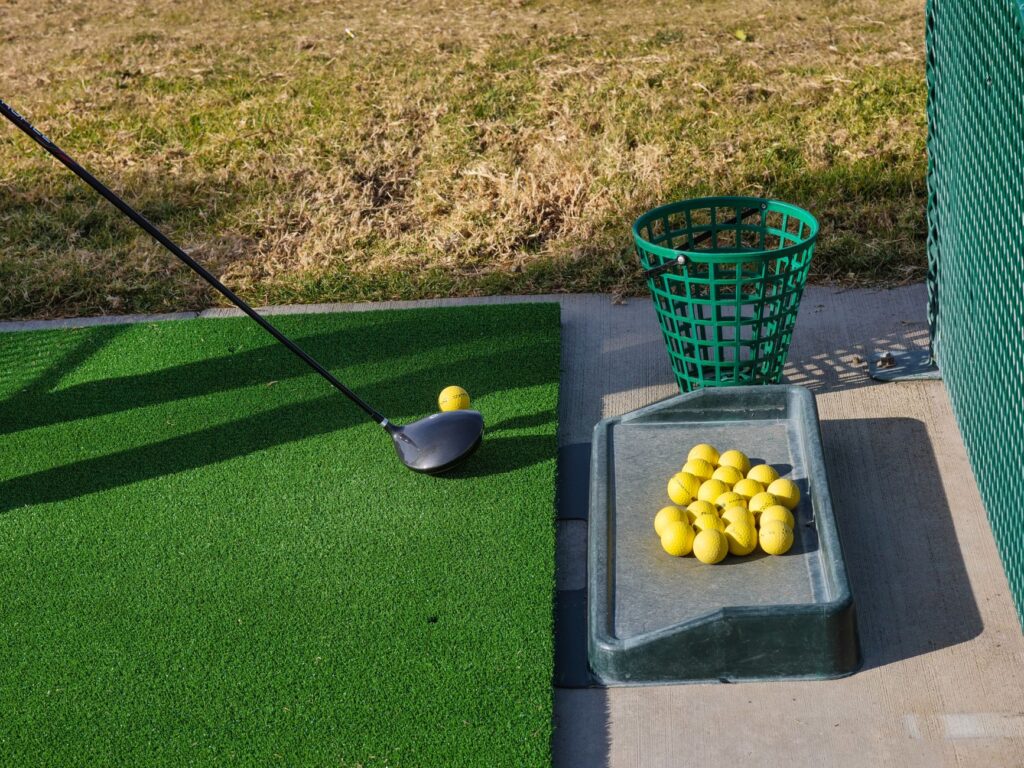 A golfer practicing their swing at a driving range, focusing on improving their golf shot accuracy.
