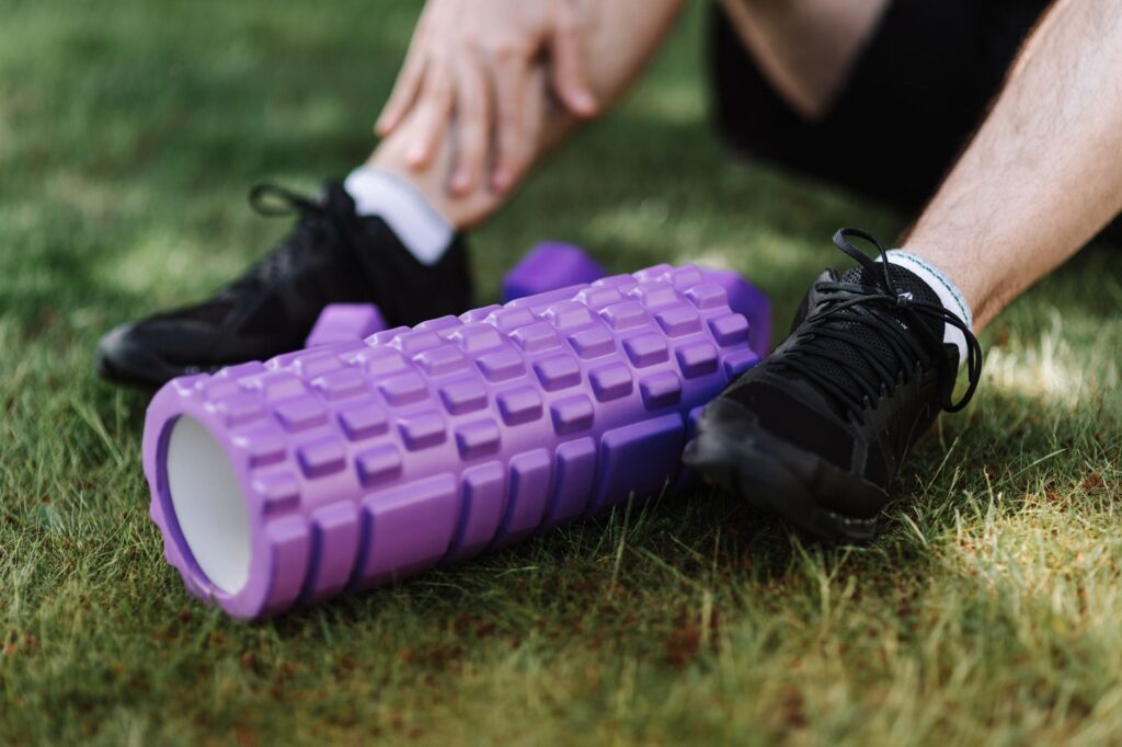 A golfer using a foam roller on their leg muscle after playing — golf recovery tips