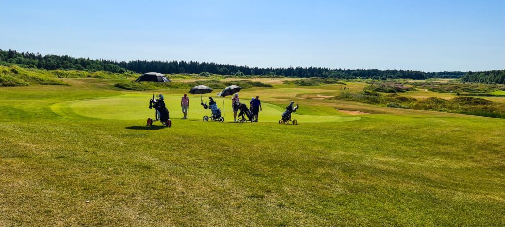A golfer using a weather-resistant umbrella on a Dungeness golf course — golf accessories Dungeness
