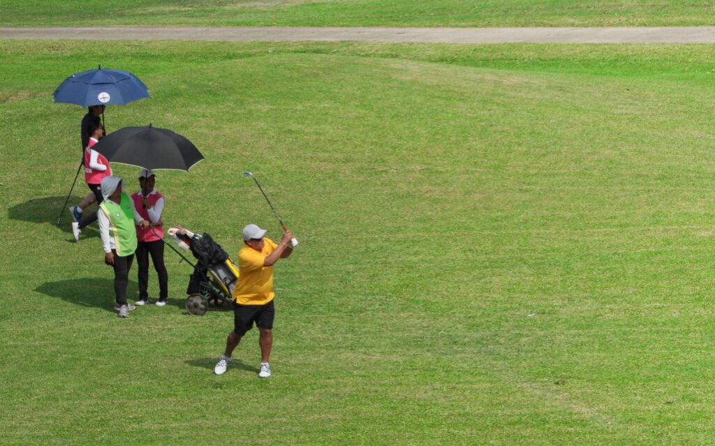 A golfer using a wind-resistant umbrella on the course. — golf equipment Dungeness