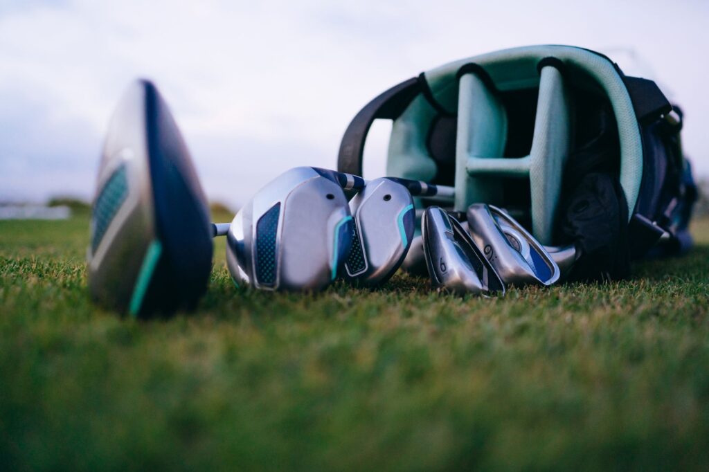 An assortment of beginner golf clubs and gear laid out on a grassy area. — golfing in Dungeness for beginners