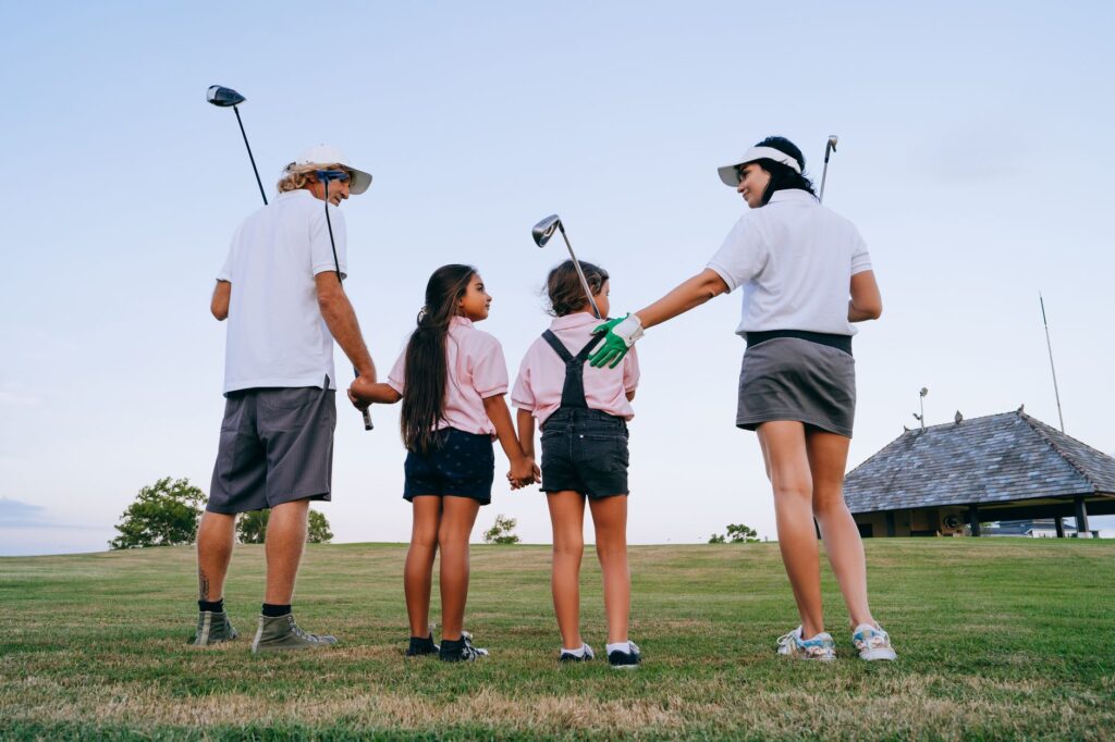 Parents helping kids with their golf equipment at the course. — family golf Dungeness