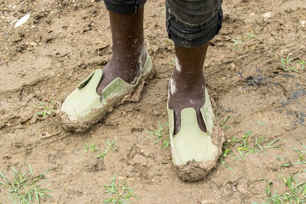 A close-up of golfers' shoes in muddy conditions after rain — weather impact on Dungeness golf